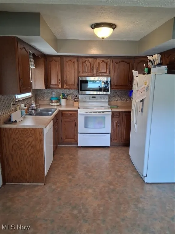 Kitchen featuring fridge, white electric range oven, light countertops, and decorative backsplash