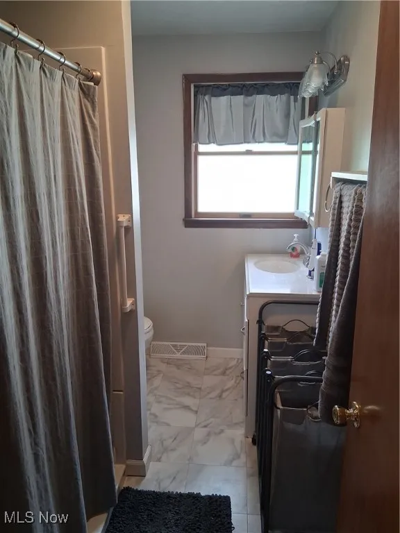 Bathroom featuring marble finish floors, vanity, and a shower with curtain