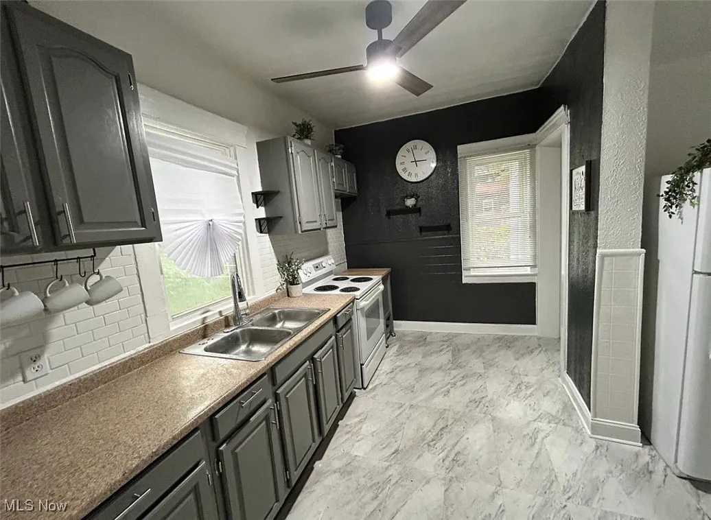 Kitchen with ceiling fan, healthy amount of natural light, white appliances, and backsplash