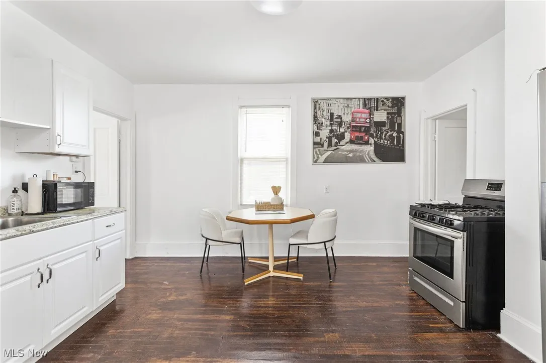 Kitchen with stainless steel gas range, white cabinetry, dark wood-style floors, and light countertops
