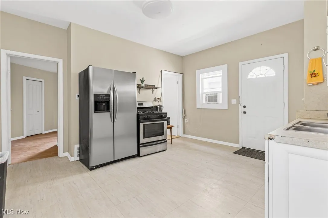 Kitchen with appliances with stainless steel finishes, light countertops, and open shelves