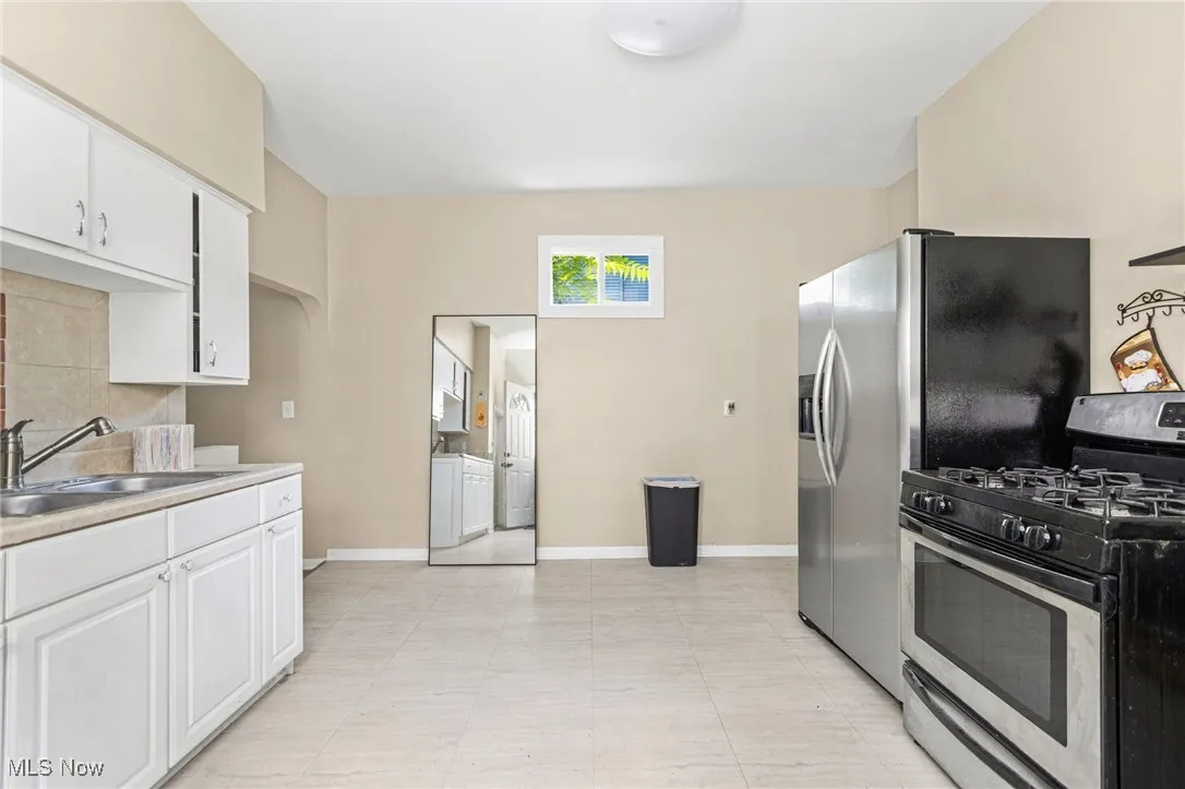 Kitchen featuring gas stove, white cabinets, washing machine and clothes dryer, and light countertops