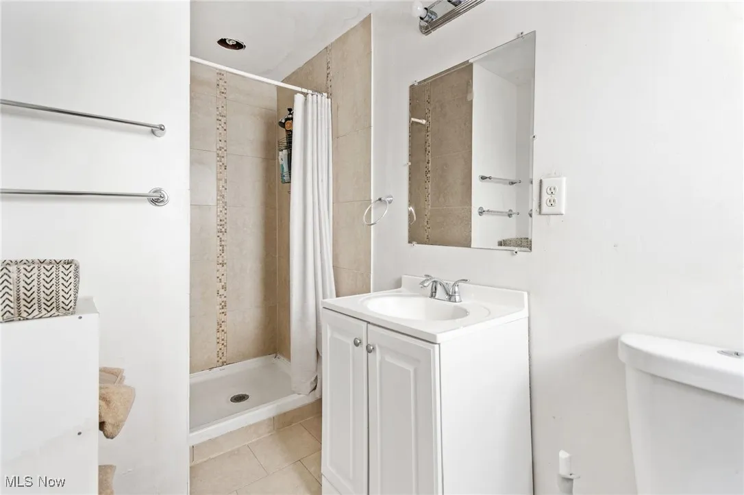 Full bath with vanity, a shower stall, and tile patterned flooring