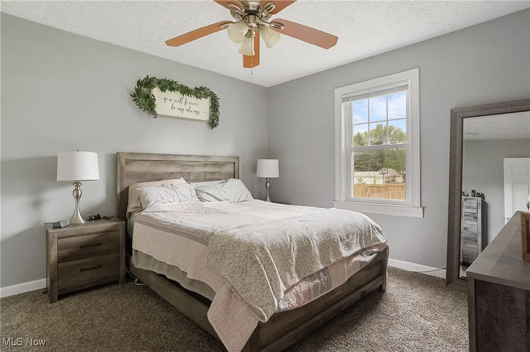 Bedroom with carpet flooring, a textured ceiling, and ceiling fan