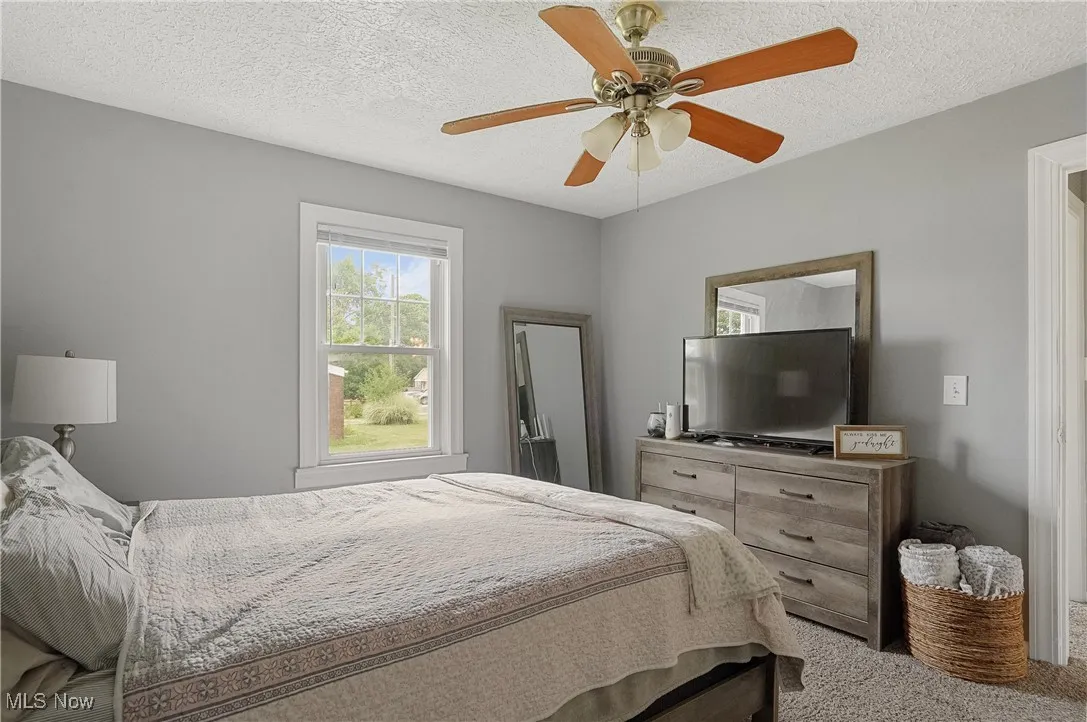 Bedroom with carpet, a textured ceiling, and ceiling fan