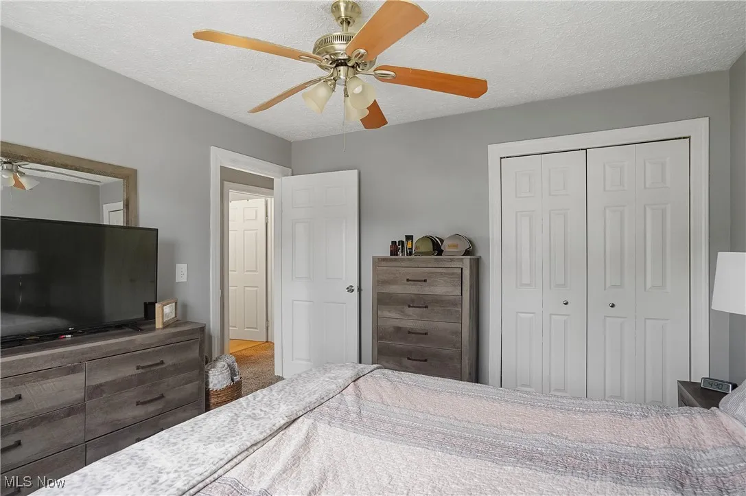 Bedroom featuring a closet, ceiling fan, and a textured ceiling