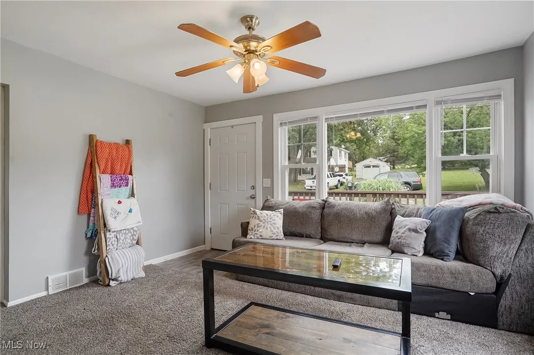 Living area featuring a ceiling fan and carpet flooring