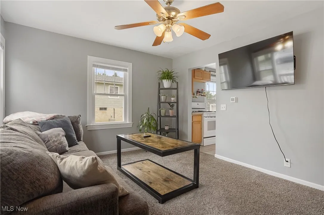 Living area featuring light colored carpet and ceiling fan