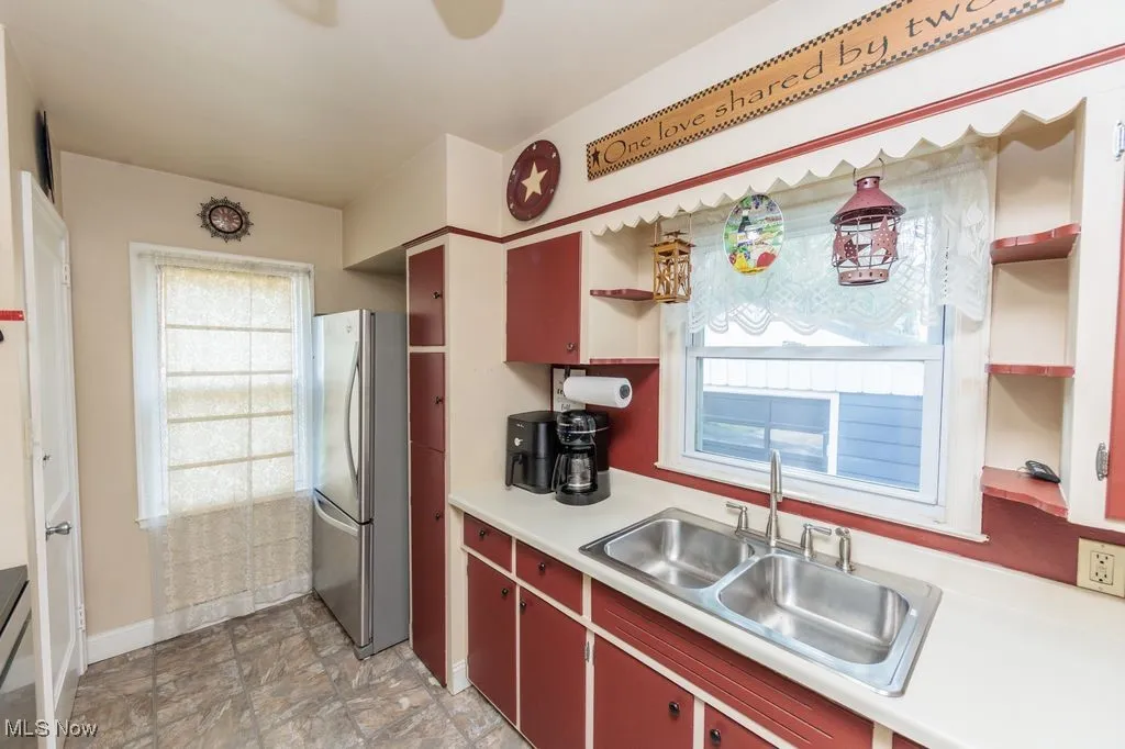 Kitchen featuring open shelves, freestanding refrigerator, plenty of natural light, and light countertops