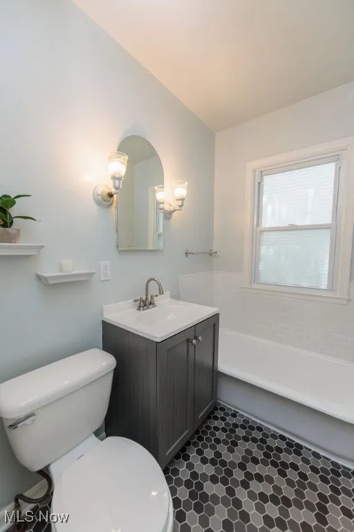 Full bathroom featuring vanity, a garden tub, vaulted ceiling, and tile patterned flooring