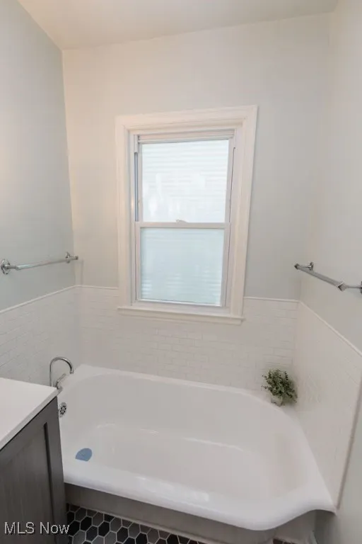 Bathroom with a bath, vanity, tile patterned flooring, and wainscoting