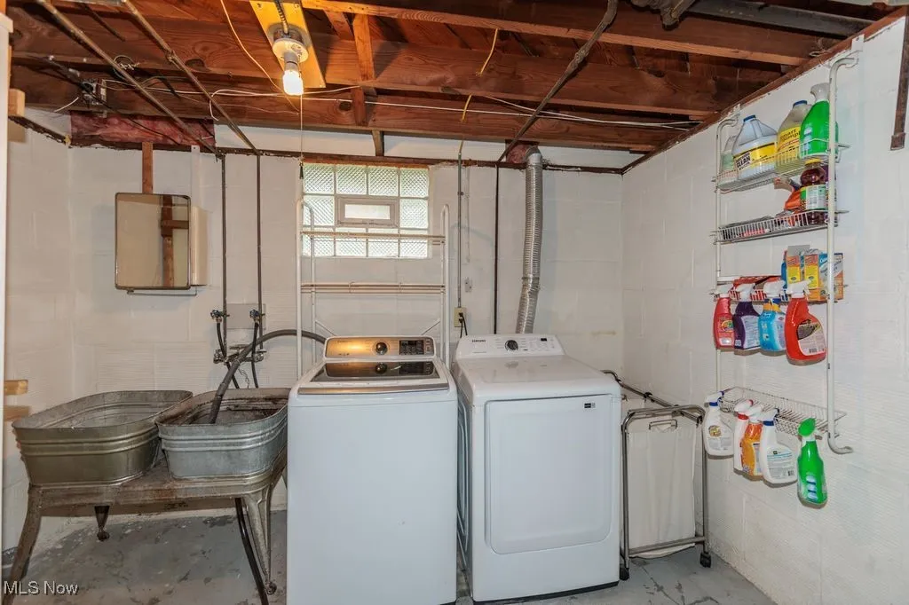 Washroom with washer and clothes dryer and concrete block wall