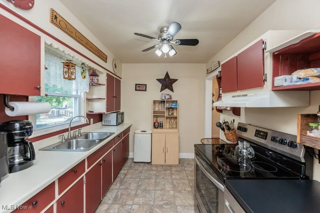 Kitchen with electric range, open shelves, red cabinets, and ceiling fan
