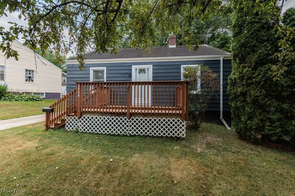 Back of property with a chimney, a yard, and a deck
