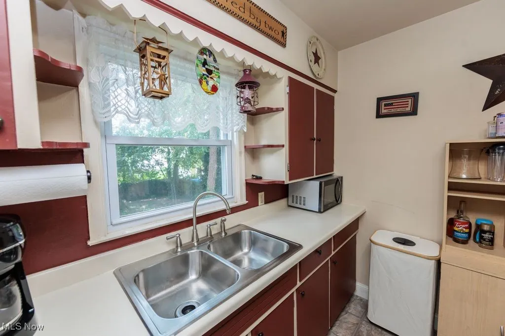 Kitchen with open shelves, black microwave, and light countertops