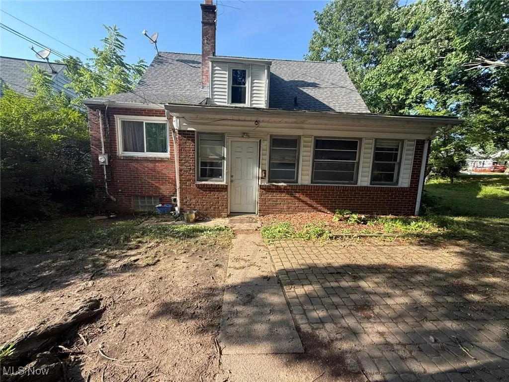 Bungalow-style house with brick siding, a chimney, and roof with shingles