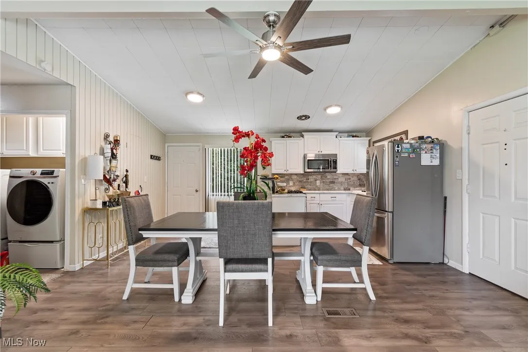 Dining space with a ceiling fan, washer / dryer, and dark wood-type flooring