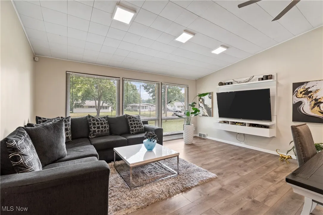Living area featuring healthy amount of natural light, wood finished floors, lofted ceiling, and a ceiling fan