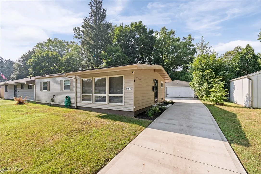 View of front facade with a front lawn, an outdoor structure, and a garage