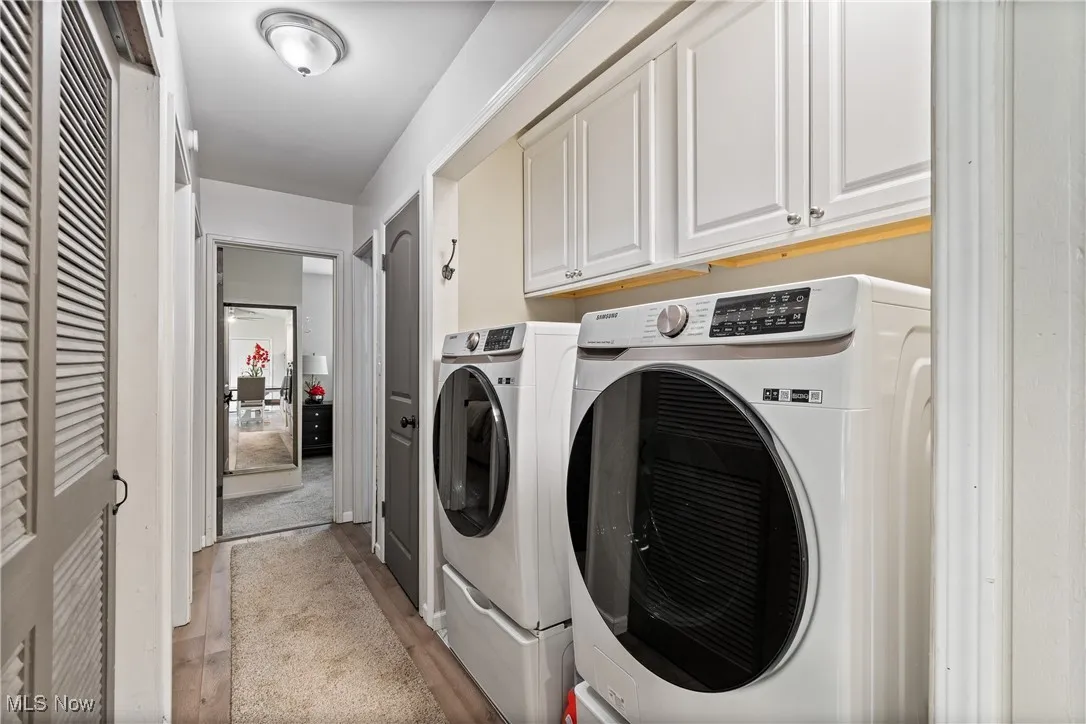 Washroom with cabinet space, washer and dryer, and light wood-style floors