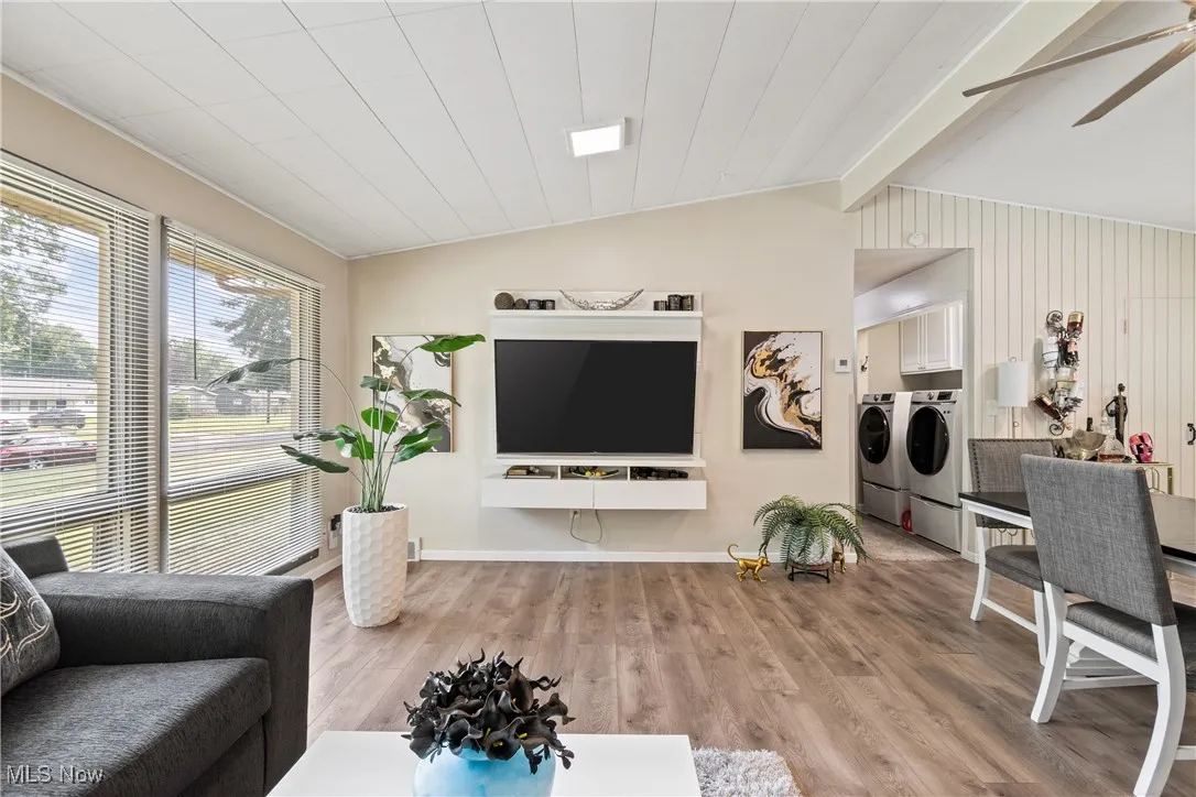 Living room featuring washer and clothes dryer, light wood-style floors, and ceiling fan