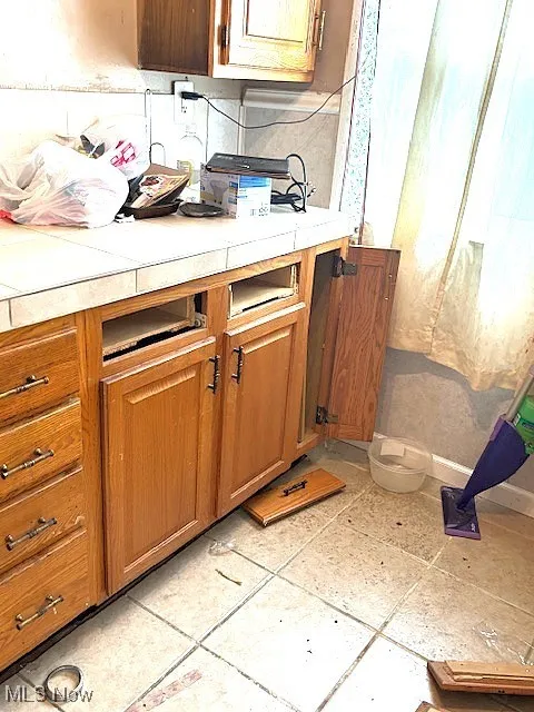 Kitchen with light countertops, brown cabinets, and light tile patterned floors