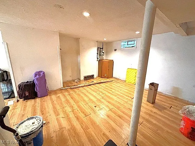 Spare room featuring wood finished floors, recessed lighting, and a textured ceiling