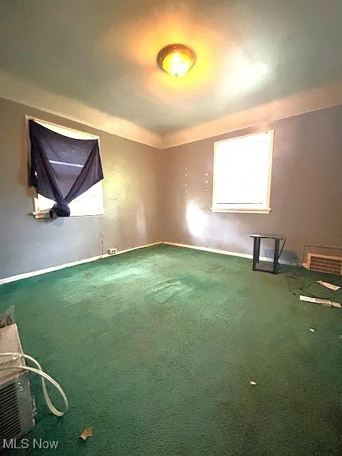 Carpeted spare room featuring baseboards