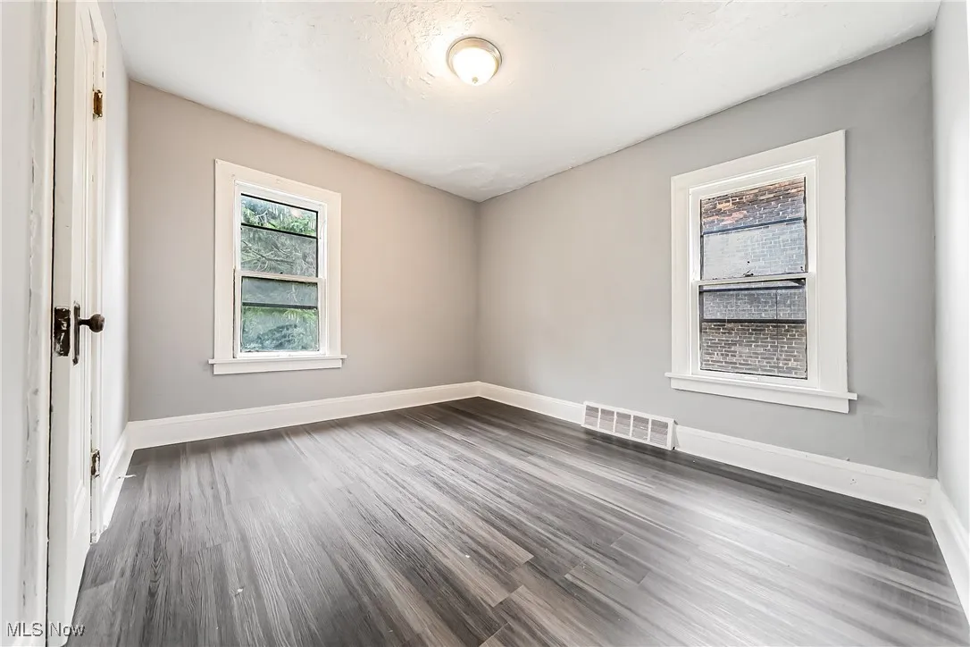 Spare room with dark wood-style floors and baseboards