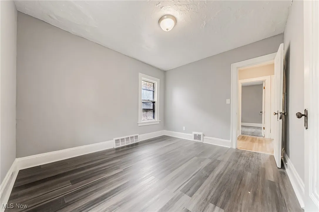 Spare room with dark wood-style floors and baseboards