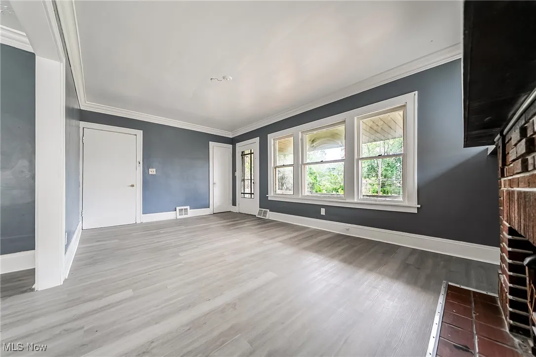 Unfurnished living room with wood finished floors and ornamental molding