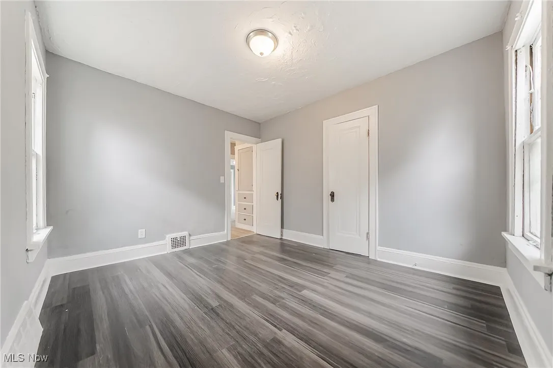Unfurnished bedroom with dark wood-style flooring and a closet