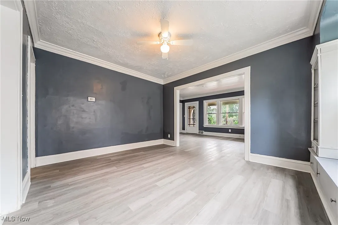 Empty room featuring wood finished floors, a textured ceiling, and ceiling fan