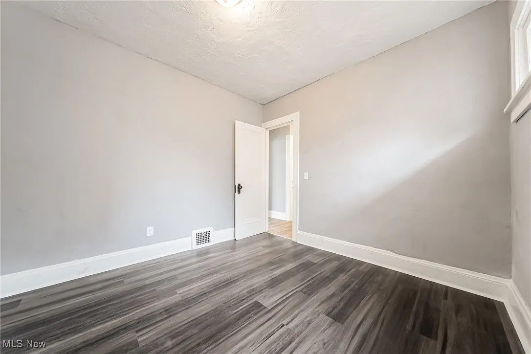 Unfurnished room featuring dark wood-style flooring and a textured ceiling