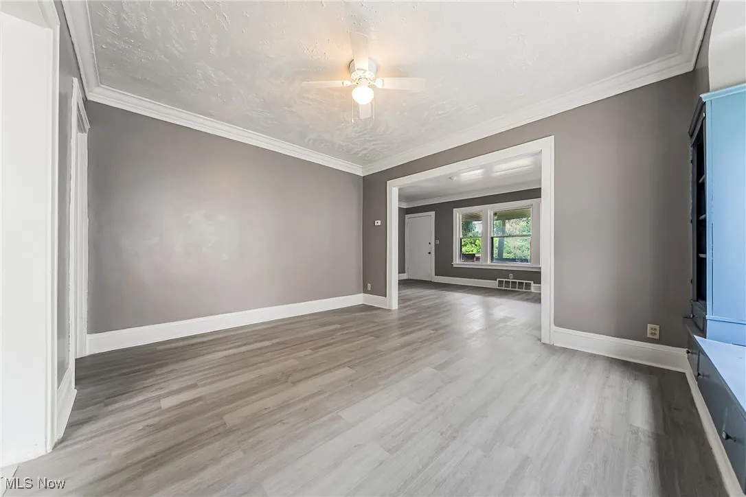 Spare room with wood finished floors, ceiling fan, a textured ceiling, and crown molding