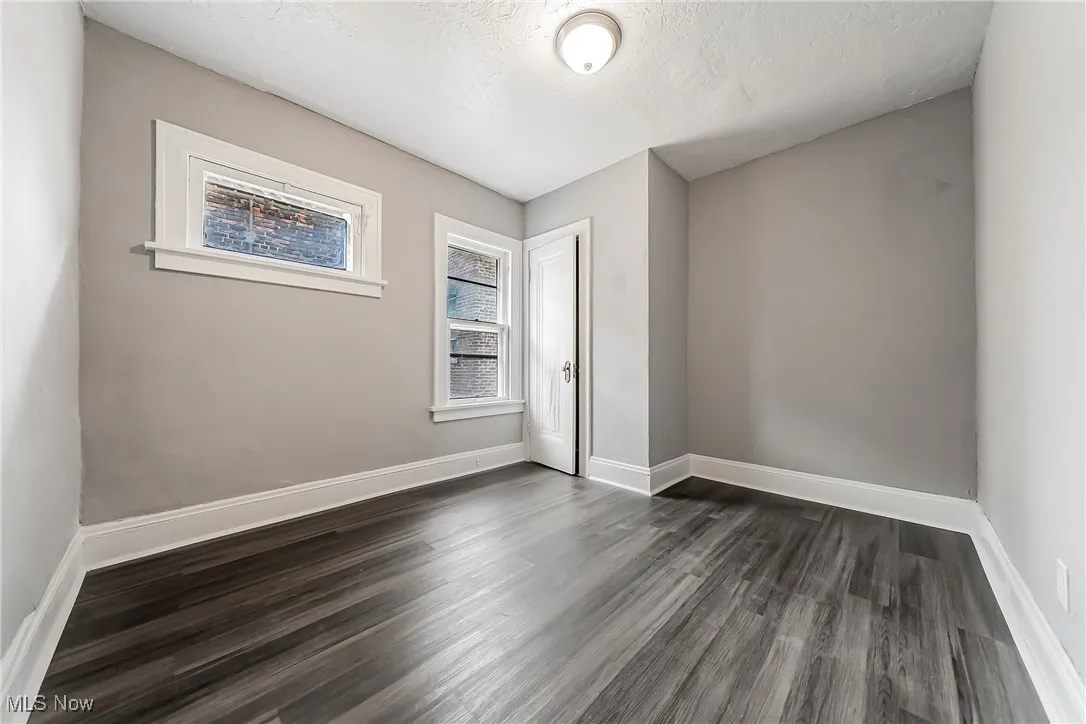 Unfurnished room featuring dark wood-style flooring and a textured ceiling