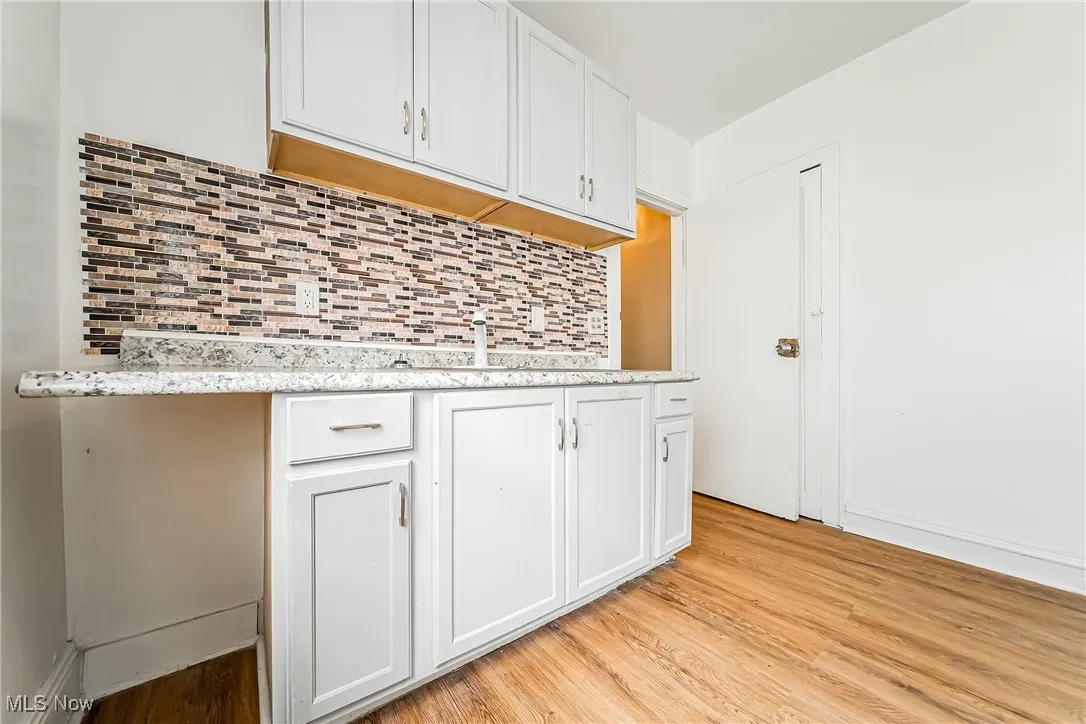 Kitchen with light wood-style flooring, tasteful backsplash, and white cabinets