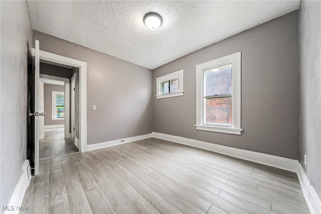 Empty room with a textured ceiling and light wood-style floors