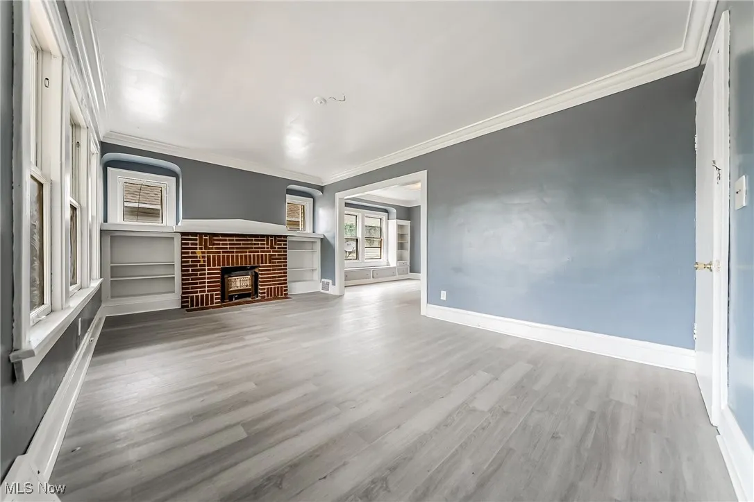 Unfurnished living room featuring ornamental molding, wood finished floors, and a fireplace