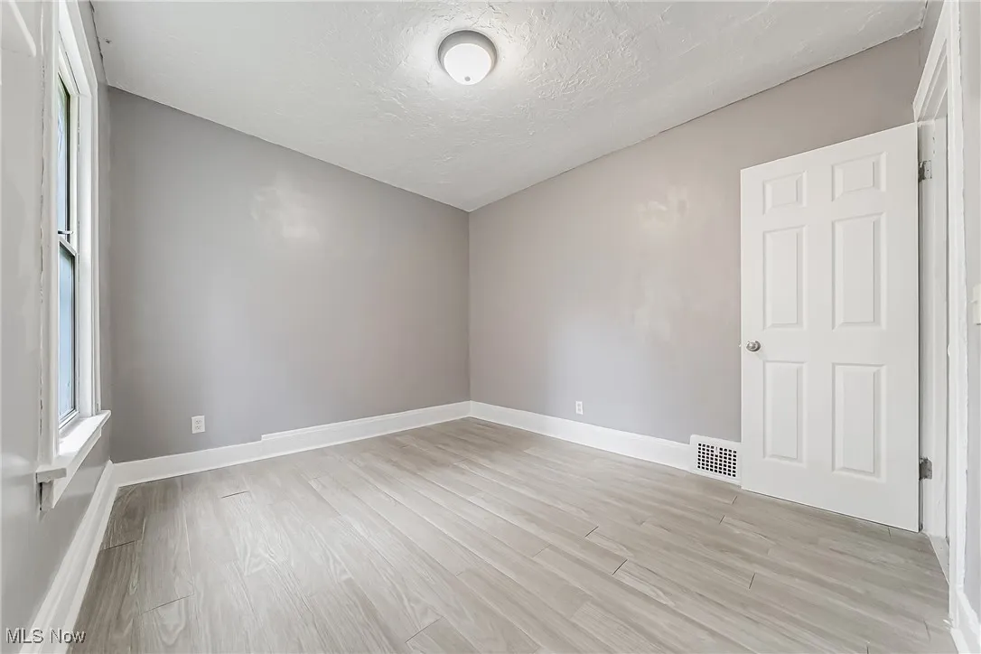 Empty room featuring light wood-style floors and a textured ceiling