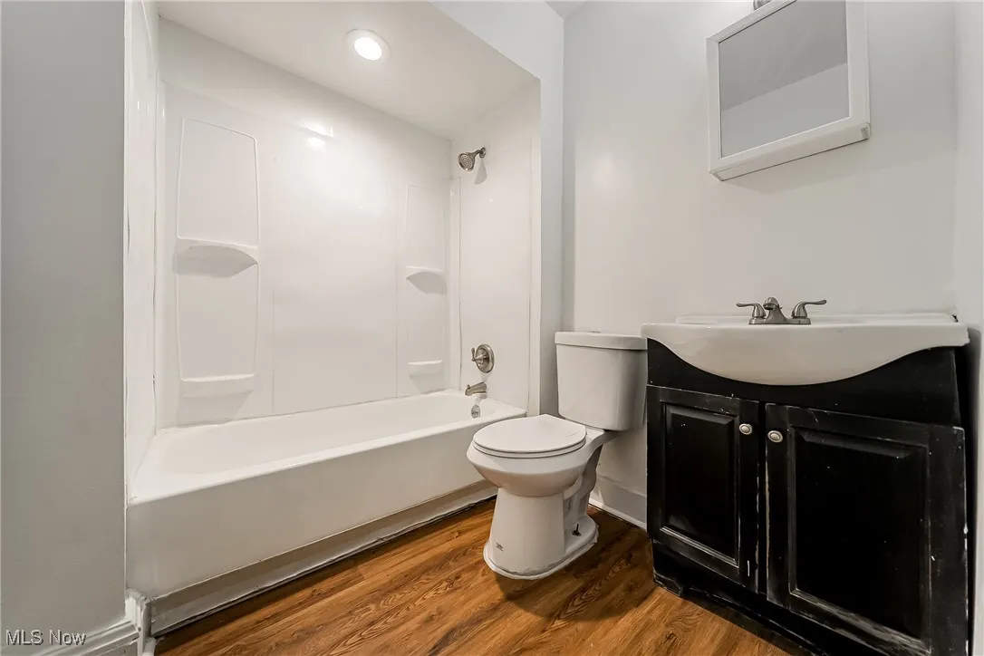 Full bath featuring vanity, shower / bath combination, wood finished floors, and recessed lighting