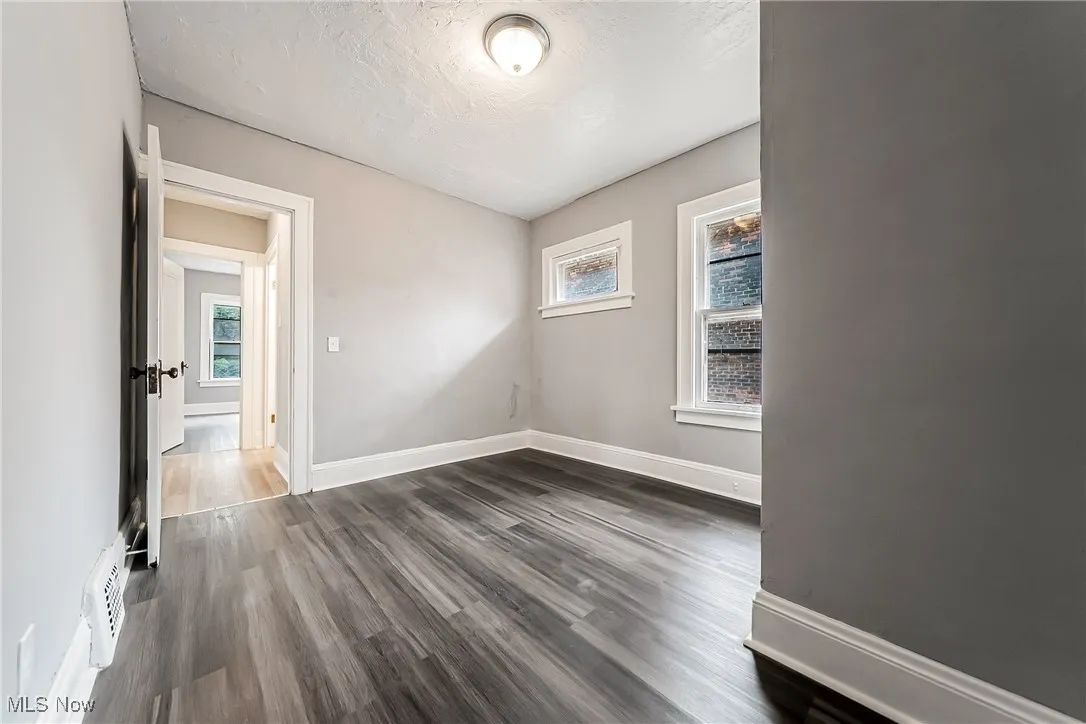 Unfurnished room with dark wood finished floors and a textured ceiling