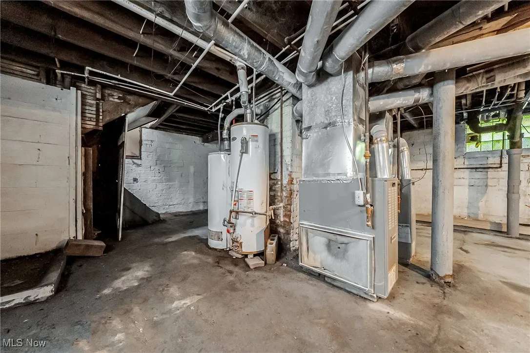 Unfinished below grade area featuring gas water heater and heating unit