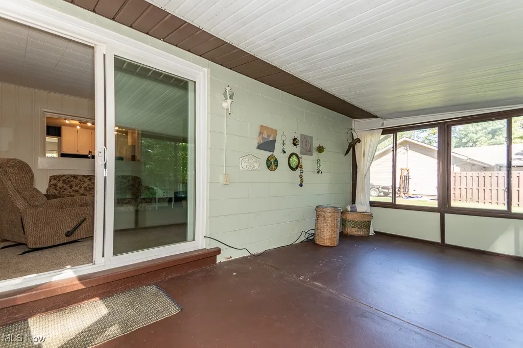 Unfurnished sunroom featuring concrete flooring and concrete block wall