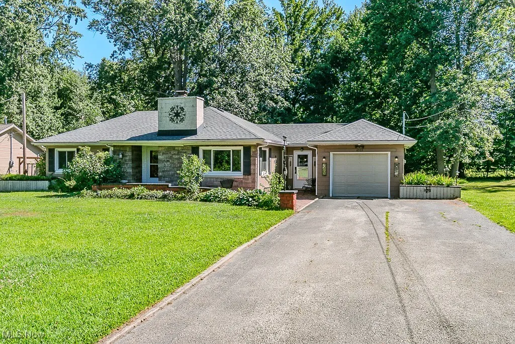 Single story home with asphalt driveway, an attached garage, roof with shingles, a front lawn, and a chimney