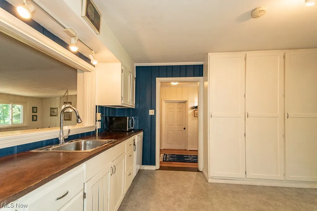 Kitchen with dark countertops, white cabinets, and stainless steel microwave