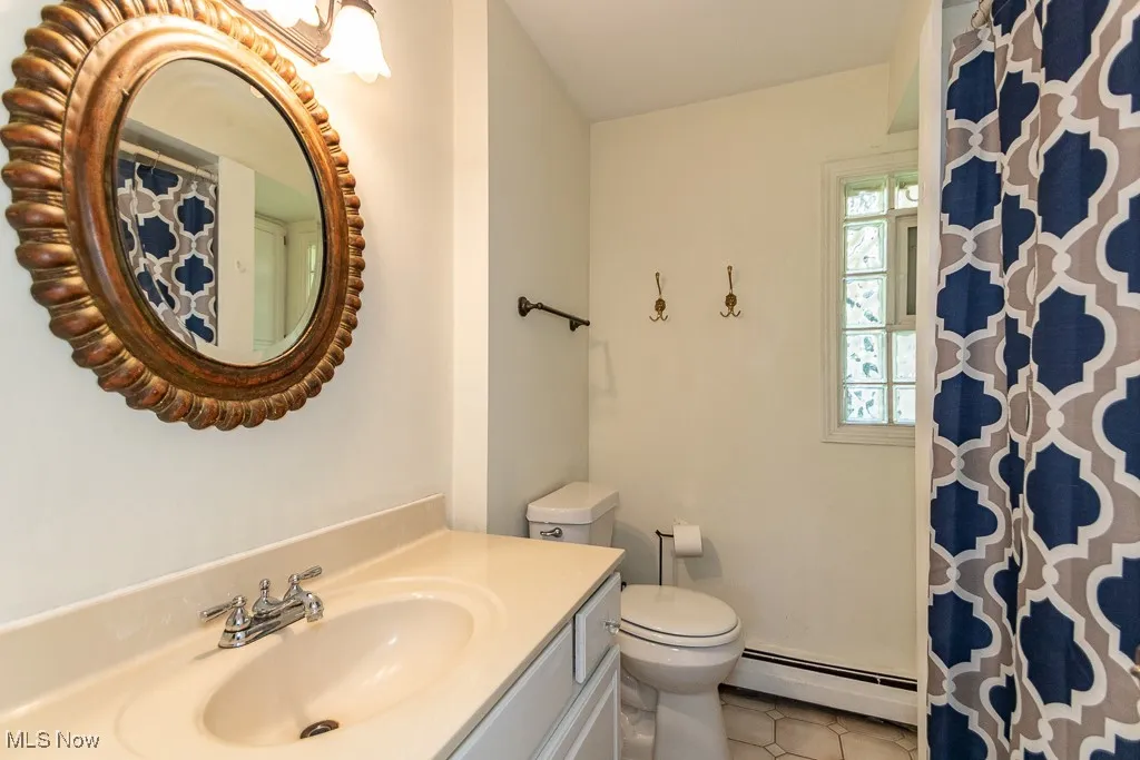 Bathroom featuring vanity, a baseboard heating unit, tile patterned floors, and a shower with curtain
