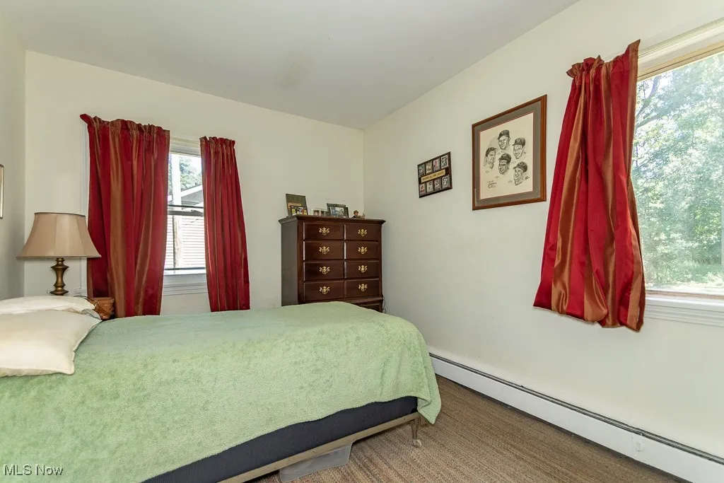 Bedroom with a baseboard radiator and multiple windows