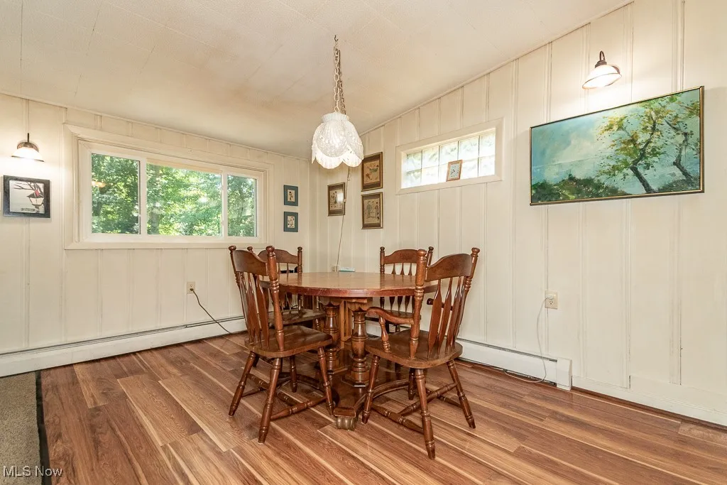 Dining space featuring wood finished floors, a baseboard heating unit, and a decorative wall