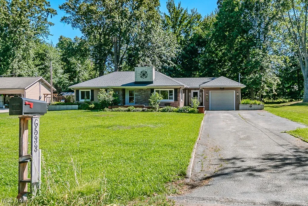 View of front facade featuring a garage, driveway, and a front lawn